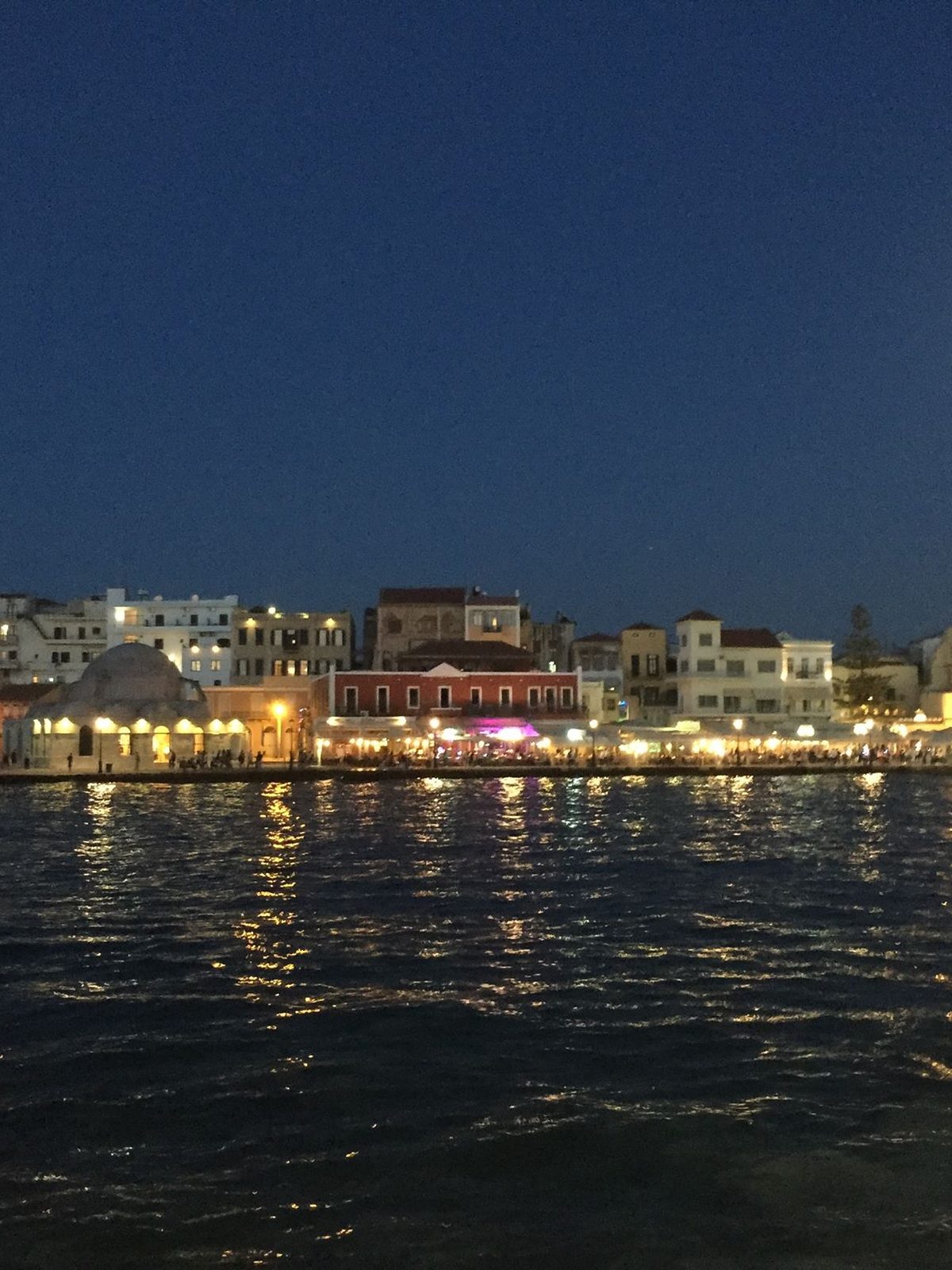 Chania old harbour on Crete lit at night, reflected in the water